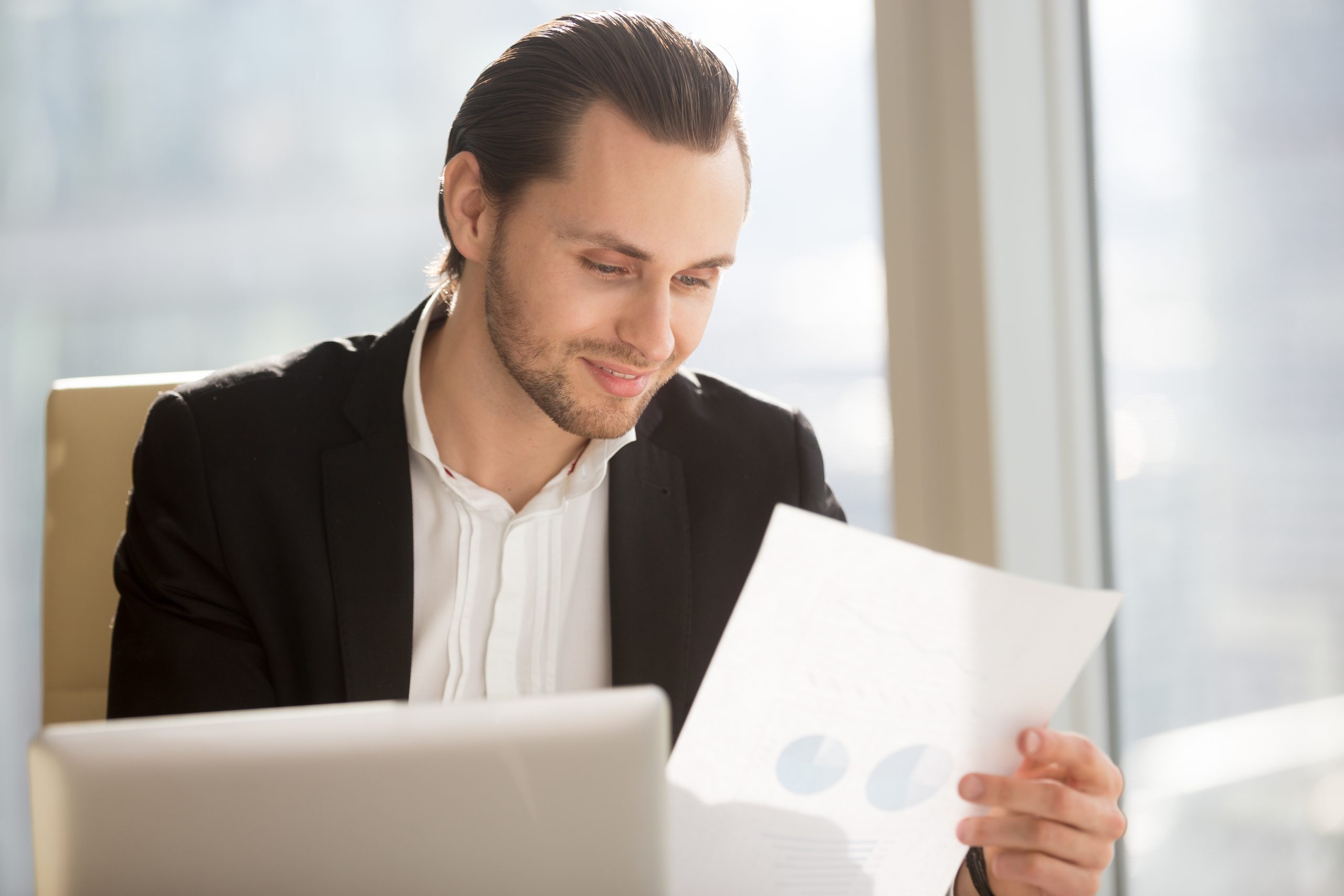 Smiling businessman looking at financial report at workplace