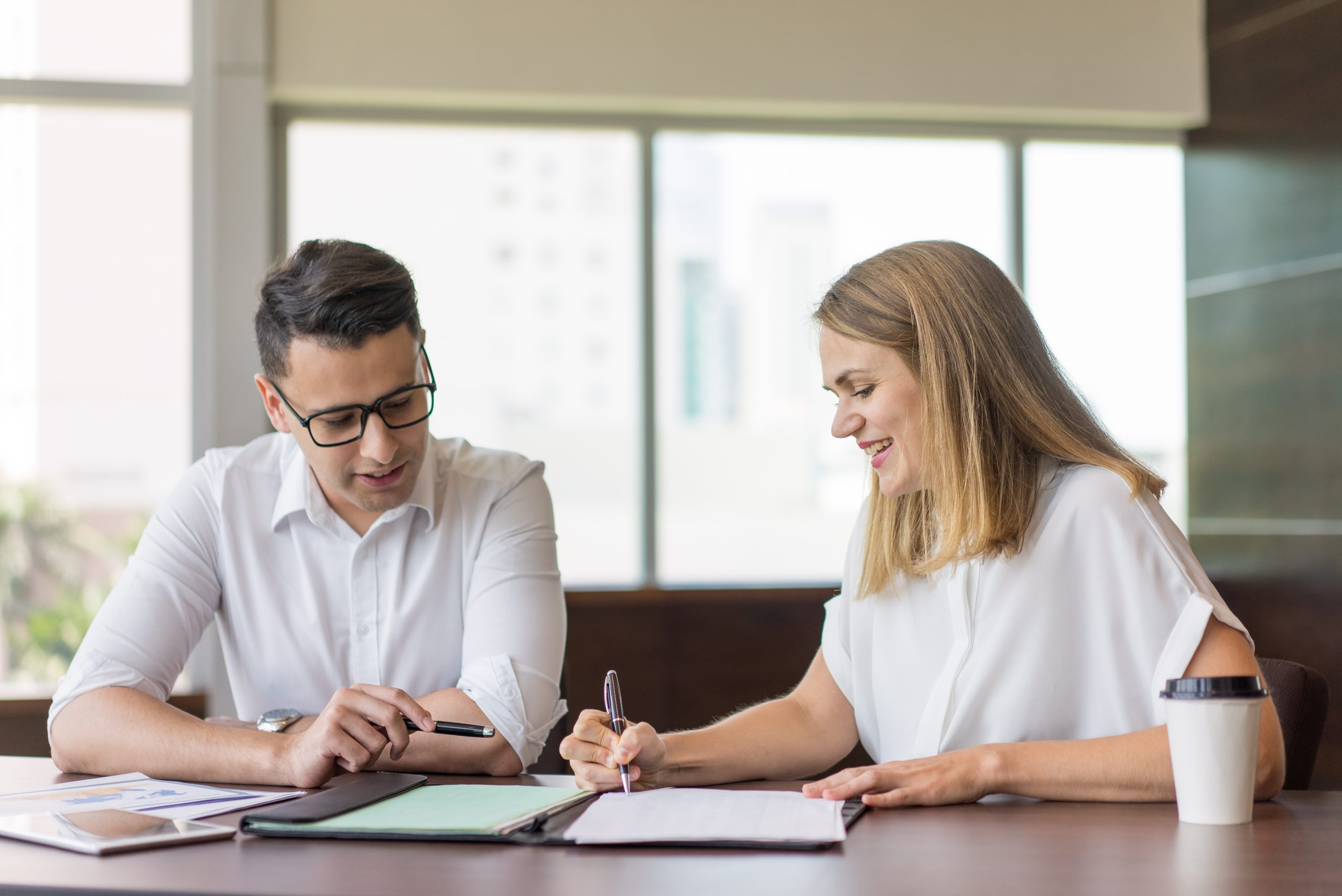 Smiling young colleagues working with documents in office